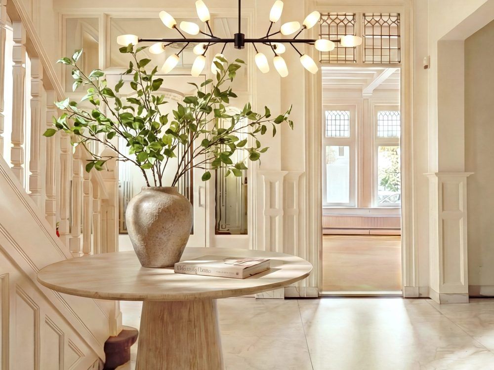 Entrance hall at CreativeGrounds with a round table, a vase of white flowers and a chandelier