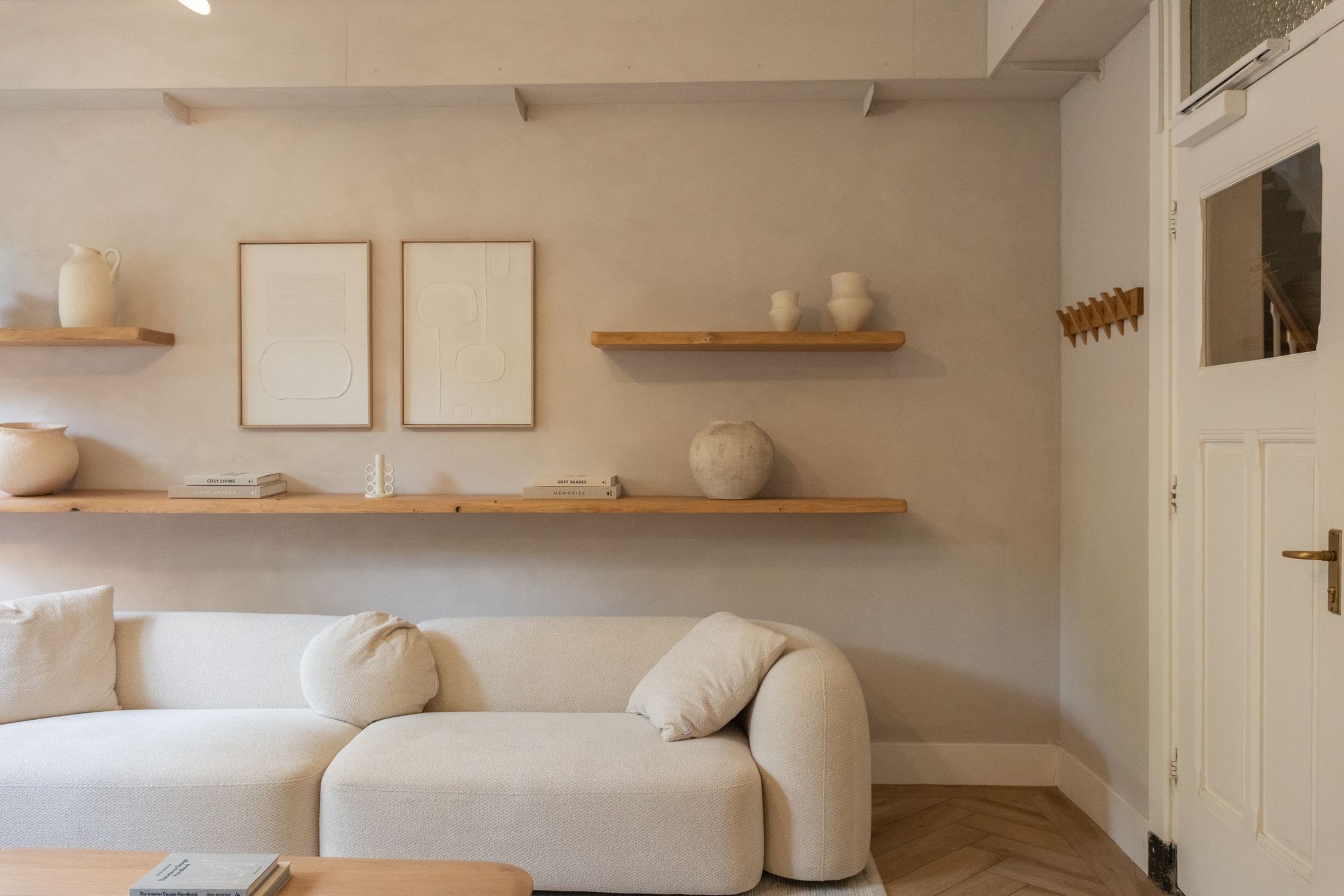 Mission meeting room at CreativeGrounds coworking, Amsterdam Oud-Zuid, with a white sofa, wooden shelves with vases and framed art