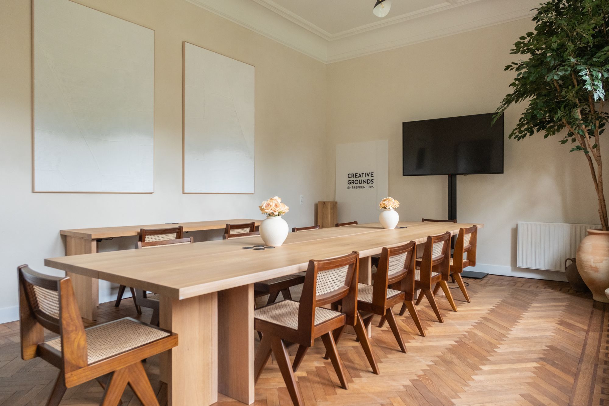 Oak meeting room at CreativeGrounds coworking, Amsterdam Oud-Zuid, with a long oak table, cane chairs and a screen