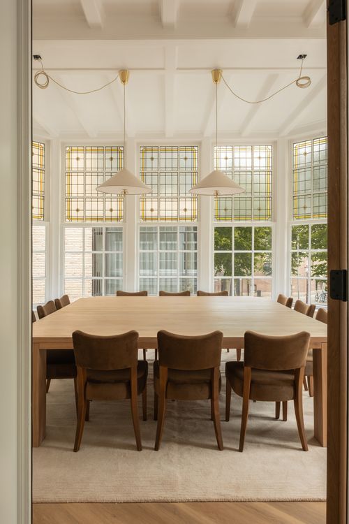 Boardroom at CreativeGrounds with a large oak table, velvet chairs and stained-glass windows, Amsterdam Oud-Zuid