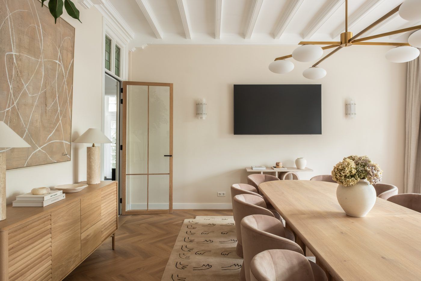 Meeting room with a long oak table, blush upholstered chairs and a screen at CreativeGrounds, Amsterdam Oud-Zuid