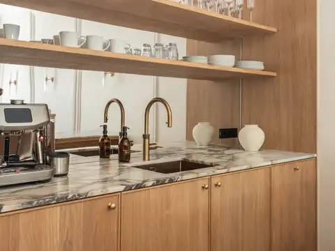 Pantry with an espresso machine, a marble counter and shelves with cups