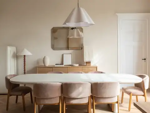 Dining table with pink velvet chairs, an oak sideboard and a pendant lamp