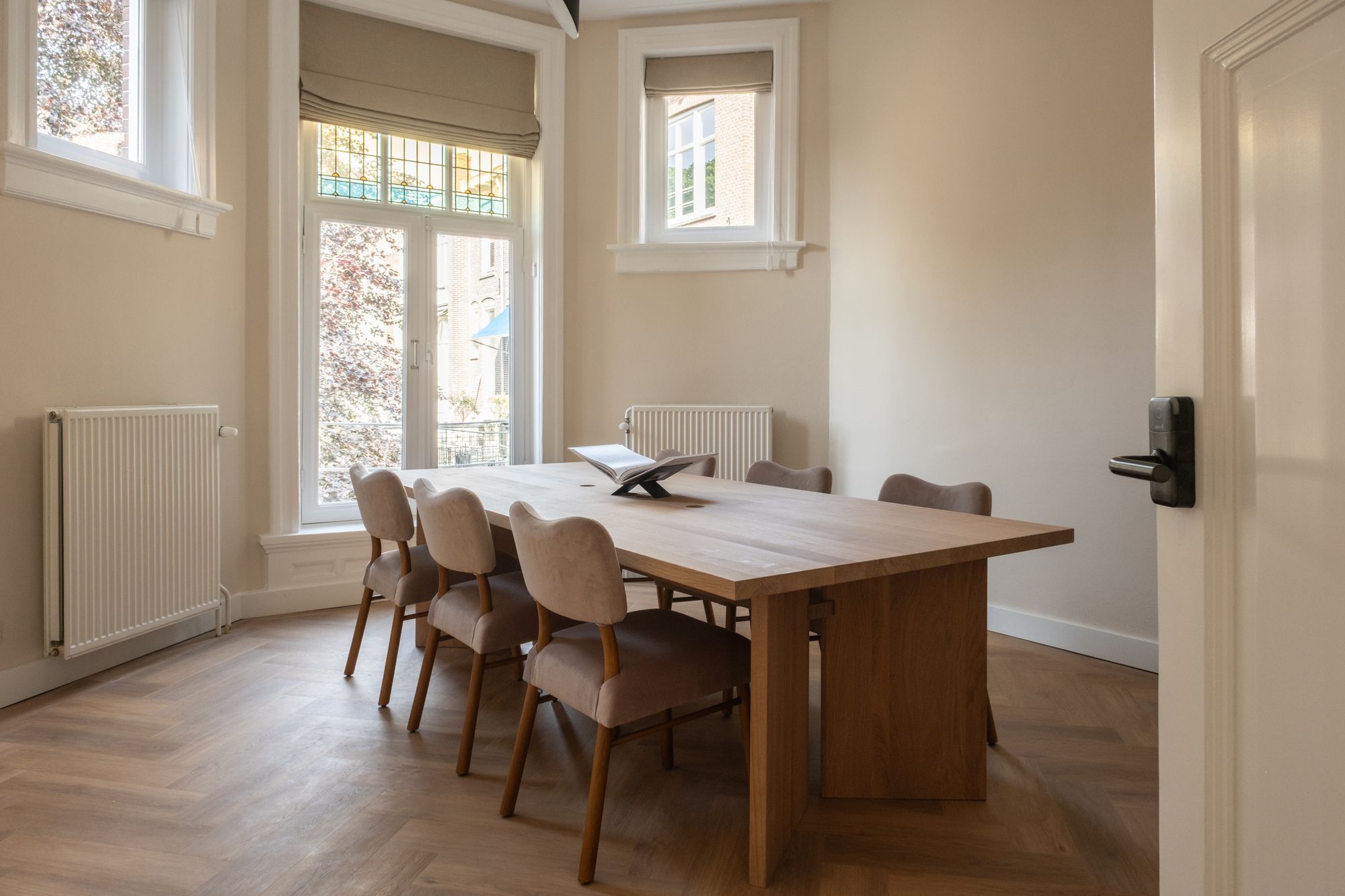 Meeting room with an oak table and upholstered chairs, connected to the private office suite by a door with a smart lock, CreativeGrounds Amsterdam Oud-Zuid
