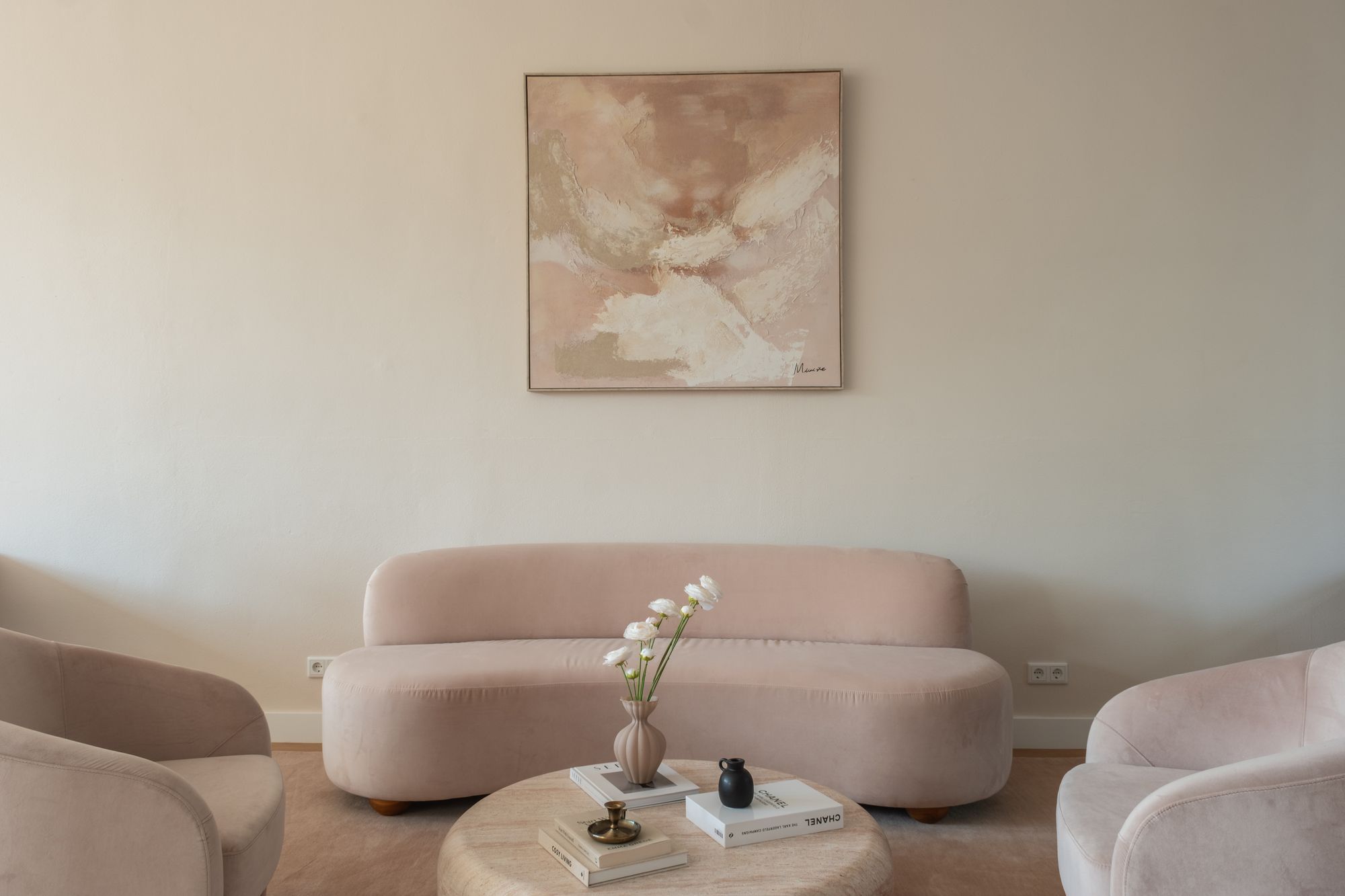 Lounge corner with a pink curved sofa, armchairs, a round coffee table and an abstract artwork inside a CreativeGrounds private office suite, Amsterdam Oud-Zuid